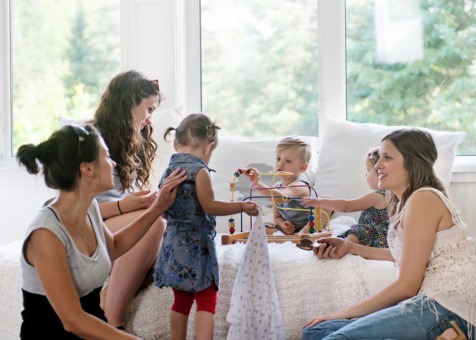Alt text: Mums and toddlers sitting together indoors, playing with toys and interacting.
